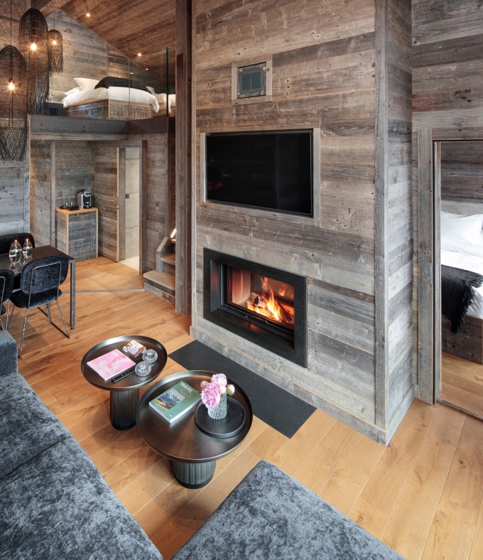 Le Penthouse Le Sommet offre un espace de vie chaleureux avec chemin&eacute;e et vue sur les Alpes valaisannes.